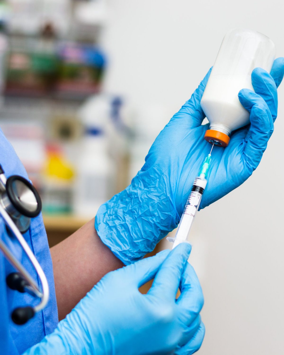 the veterinarian women with blue gloves and  stethoscope extract a white drug with a syringe